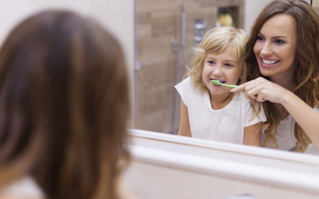 Mother teaching daughter how to make brushing fun